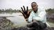 A man showing his hand dirty with oil after plunging it in the Niger Delta